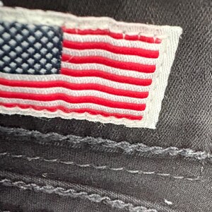 Puede incluir: Una taza de cer&aacute;mica blanca con asa negra y el texto "But First, Coffee" en negrita negra. La taza se encuentra sobre un fondo borroso, sugiriendo un ambiente acogedor.