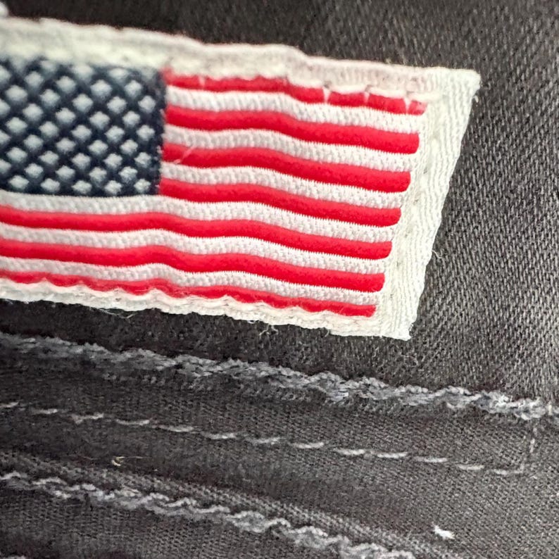 Puede incluir: Una taza de cer&aacute;mica blanca con asa negra y el texto "But First, Coffee" en negrita negra. La taza se encuentra sobre un fondo borroso, sugiriendo un ambiente acogedor.