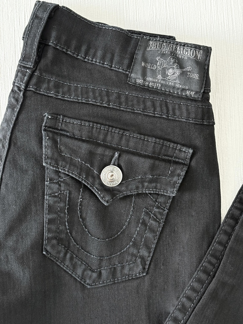 Puede incluir: Una taza de cer&aacute;mica blanca con un asa negra y el texto "But First, Coffee" en negrita negra. La taza est&aacute; sobre una superficie de madera. La taza mide 10 cm de alto.