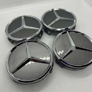 Puede incluir: Cuatro tapacubos plateados y grises para ruedas de coche con el logotipo de Mercedes-Benz. Cada tapacubos presenta un fondo gris con un emblema de estrella de tres puntas plateada y un anillo exterior plateado. Los tapacubos son circulares y parecen nuevos.