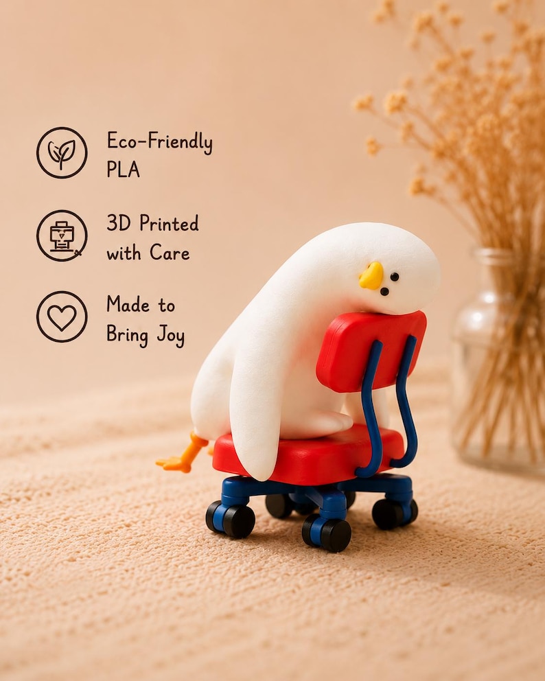 K&ouml;nnte beinhalten: Eine wei&szlig;e, abgerundete pinguinartige Figur mit gelbem Schnabel, die auf einem kleinen roten B&uuml;rostuhl mit blauen Beinen und schwarzen Rollen sitzt. Der Text links lautet: Eco-Friendly PLA, 3D Printed with Care, Made to Bring Joy.