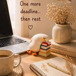 Puede incluir: Una peque&ntilde;a figura de pato blanco descansando sobre una pila de cuatro libros coloridos. El texto superior dice One more deadline... then rest con un s&iacute;mbolo de coraz&oacute;n. La escena incluye un port&aacute;til, una taza, un cuaderno, un bol&iacute;grafo y un florero.