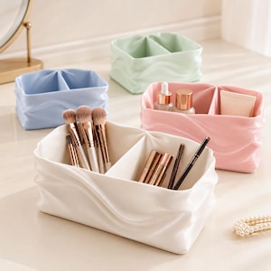 Peut inclure: Un ensemble de quatre organisateurs de bureau rectangulaires avec une texture douce rappelant le tissu drapé. Les organisateurs sont disponibles en blanc, rose pastel, bleu clair et vert pâle. Chaque contenant possède un séparateur central.
