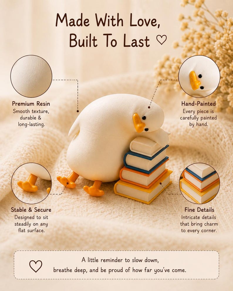 Puede incluir: Una figura de pato de resina blanca apoyando su cabeza sobre una pila de tres libros con portadas azul, naranja y amarilla. El pato tiene patas y pico naranjas. El texto incluye: Made With Love, Built To Last, Premium Resin, Hand-Painted, Stable & Secure, Fine Details y A little reminder to slow down, breathe deep, and be proud of how far you've come.