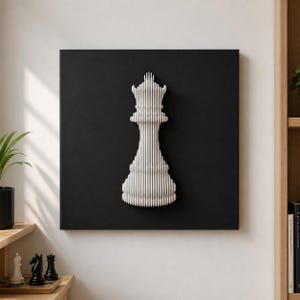 Könnte beinhalten: Ein quadratisches Wandbild mit einer weißen, dreidimensionalen, geschichteten Schachkönigin-Silhouette, die auf einem einfarbigen schwarzen Hintergrund zentriert ist. Die Figur besteht aus mehreren vertikalen Schichten, die eine gerippte Textur erzeugen.