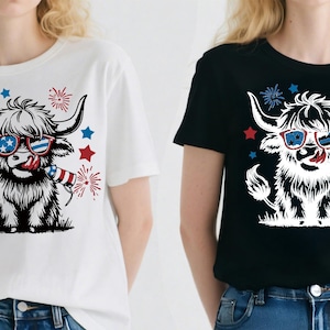 May include: White and black t-shirts featuring a Highland cow graphic wearing sunglasses with a patriotic design. The cow has its tongue out and is holding a firecracker, with red, white, and blue stars and fireworks.