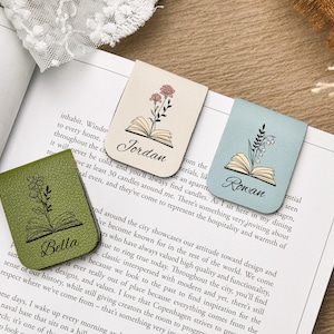 Puede incluir: Tres marcadores de cuero con dise&ntilde;os florales y nombres: Bella, Jordan y Rowan. Los marcadores son verdes, beige y azules, cada uno con una ilustraci&oacute;n floral diferente y un dise&ntilde;o de libro abierto. Est&aacute;n colocados en un libro abierto.