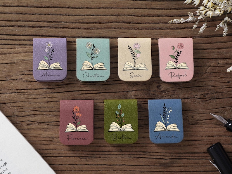 Puede incluir: Siete marcap&aacute;ginas magn&eacute;ticos coloridos con dise&ntilde;os florales y nombres. Cada marcap&aacute;ginas presenta un color diferente, incluyendo morado, verde azulado, beige, rosa, granate, verde y azul. Los nombres Miriam, Christine, Susie, Rafael, Florence, Bertha y Amanda est&aacute;n escritos.