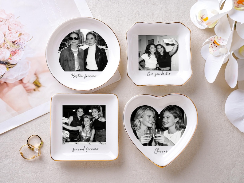 May include: Four white ceramic trinket dishes with gold rims, each featuring a black and white photo and a message. The shapes include a circle, a square, a heart, and a uniquely shaped square. Text includes "Bestie forever", "Love you bestie", "friend forever", and "Cheers".