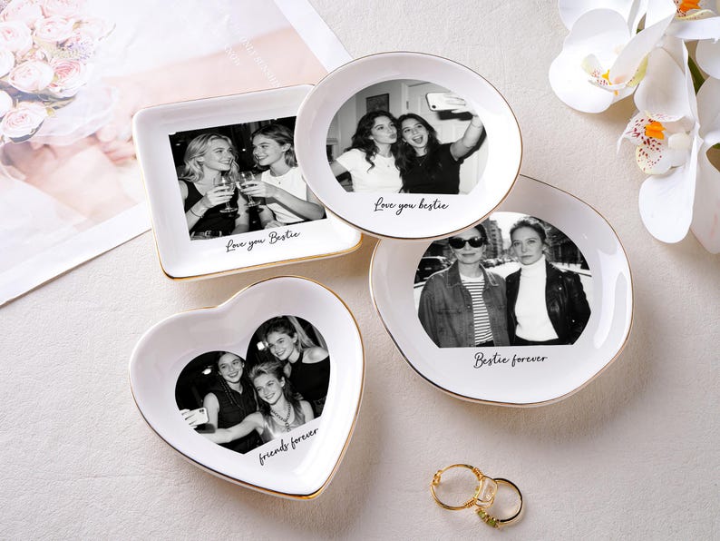 May include: Four white ceramic trinket dishes in various shapes: square, round, and heart-shaped. Each dish features a black and white photo and gold trim. Text includes "Love you Bestie" and "Bestie forever".