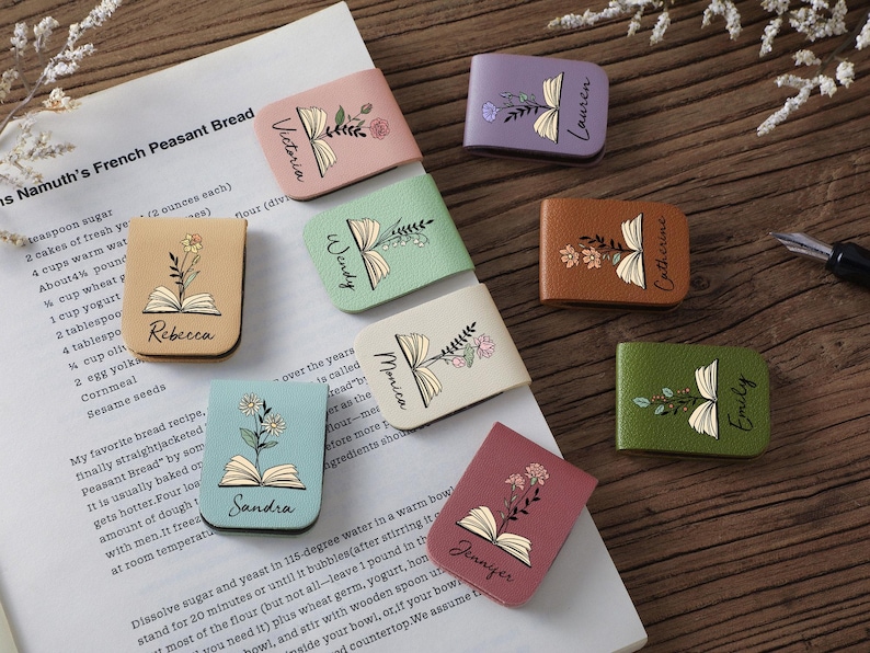 Puede incluir: Una colecci&oacute;n de sujetap&aacute;ginas de cuero de colores, cada uno con un dise&ntilde;o floral y un nombre. Los sujetap&aacute;ginas, en varios colores como rosa y verde, est&aacute;n colocados en una p&aacute;gina de recetas.