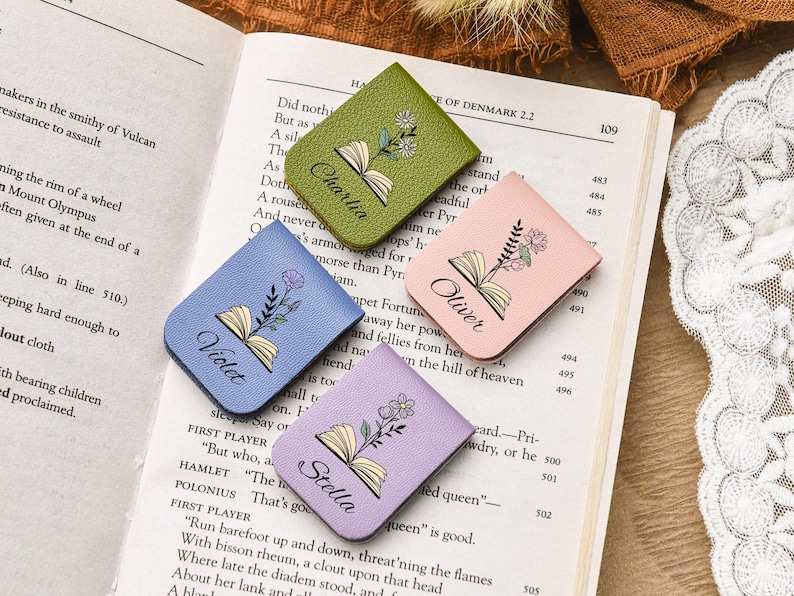 Puede incluir: Cuatro marcap&aacute;ginas de cuero de colores con dise&ntilde;os florales y nombres personalizados: Charli, Oliver, Violet y Stella. Los marcap&aacute;ginas est&aacute;n sobre un libro abierto, p&aacute;gina 109.