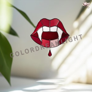 May include: A stained glass piece depicting a pair of vampire lips with sharp fangs and a blood drop. The lips are red and white, with a black outline. The text "COLORDREAMLIGHT" is visible.