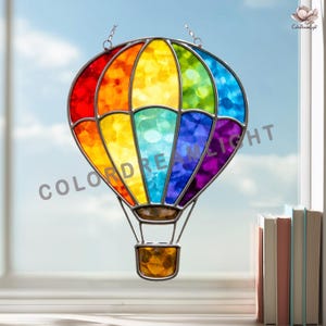 May include: A stained glass hot air balloon in a rainbow of colors, including red, orange, yellow, green, blue, and purple. The balloon has a metal frame and a basket at the bottom. The text "COLORDREAMLIGHT" is visible on the balloon.