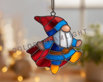 May include: Stained glass gnome ornament in a superhero costume. The gnome features a red and blue cape, hat, and outfit. The ornament is hanging from a chain and is suitable for indoor decoration. The gnome has a white beard and a brown belt.