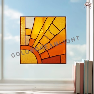 May include: A square stained glass window with a sunburst design. The artwork features a vibrant palette of yellow, orange, and amber hues, with a dark brown border. The sun's rays emanate from a semi-circle, creating a warm aesthetic.