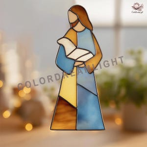 Könnte beinhalten: Buntglasfigur, die eine Person mit einem Lamm darstellt. Die Figur besteht aus geometrischen Formen in Blau-, Gelb-, Braun- und Beigetönen mit schwarzer Umrandung. Die Figur hat braunes Haar und einen Bart. Der Text "COLORDREAMLIGHT" ist sichtbar.