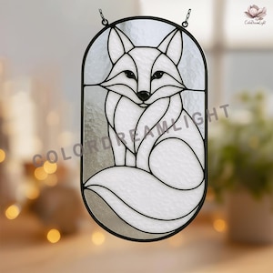 May include: Stained glass fox window hanging with a black metal frame. The fox is white with black accents, and the glass has a textured appearance. The window art is designed to hang with two small chains.