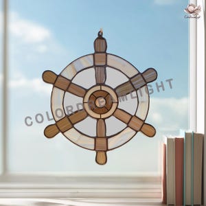 May include: Stained glass ship's wheel suncatcher with brown, beige, and cream tones. The nautical-themed decor features a circular design with spokes and a central hub. The text "COLOR DREAM LIGHT" is visible on the image.
