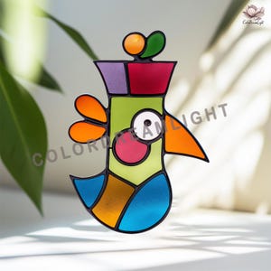May include: A colorful stained glass bird suncatcher with a geometric design. The bird features orange, green, red, purple, pink, and blue sections. The text "COLOR DREAM LIGHT" is visible on the image.