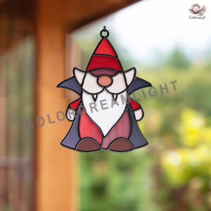 May include: A stained glass gnome with a vampire theme. The gnome wears a red hat and vest, a white beard, and a black cape. The image has the text "ColorDreamLight".