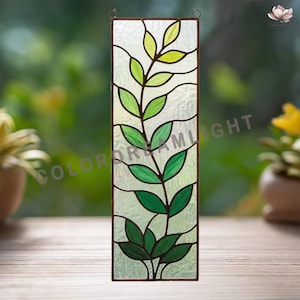 May include: A rectangular stained glass panel with a green leafy plant design. The leaves are in varying shades of green, set against a textured, clear background. The panel is framed in dark brown metal and includes the text "COLORDREAMLIGHT".