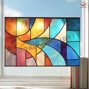 May include: A stained glass window with a black frame. The window features a colorful abstract design with shades of orange, yellow, blue, and purple. The text "COLOR DREAM LIGHT" is visible on the glass.