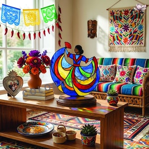 May include: A stained glass lamp featuring a figure in a flowing, multi-colored dress of blue, yellow, and red, holding a fan. The lamp sits on a wooden base, casting vibrant light reflections on a wooden table surface in a room with decor.
