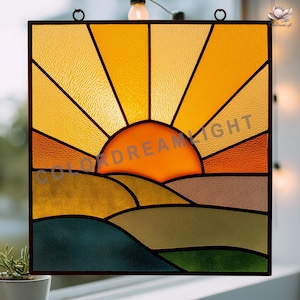 May include: A square stained glass panel showing a sunrise over rolling hills. The sun is a bright orange, with yellow rays. The hills are various shades of green, brown, and orange. The text "COLOR DREAM LIGHT" is visible.