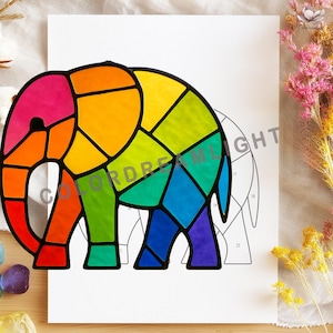 Op de afbeelding: Een kleurrijk glas-in-lood ontwerp van een olifant met een regenboog aan kleuren, waaronder roze, oranje, geel, groen, blauw en paars. Het ontwerp is zwart omlijnd en staat op een witte achtergrond. De tekst "COLORDREAMLIGHT" is zichtbaar.