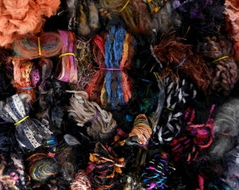 May include: A collection of colorful yarn scraps in various textures and colors, including brown, orange, black, white, blue, and green. The yarn is bundled together in a chaotic pile.