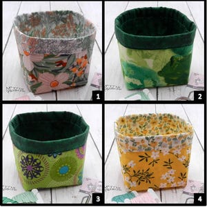 May include: Four fabric storage baskets with floral patterns. Each basket has a different design: pink and orange flowers, green leaves, green and yellow circles, and yellow flowers. The rims are a solid green color.