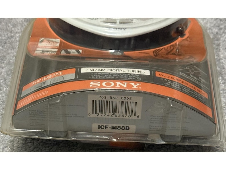 Pu&ograve; includere: Una nuova radio per bici con computer di bordo e sintonizzazione digitale Sony ICF-M88B FM/AM, confezionata in una custodia di plastica trasparente. La confezione presenta accenti arancioni e neri con il logo Sony e informazioni sul prodotto. La radio &egrave; progettata per l'uso in bicicletta.