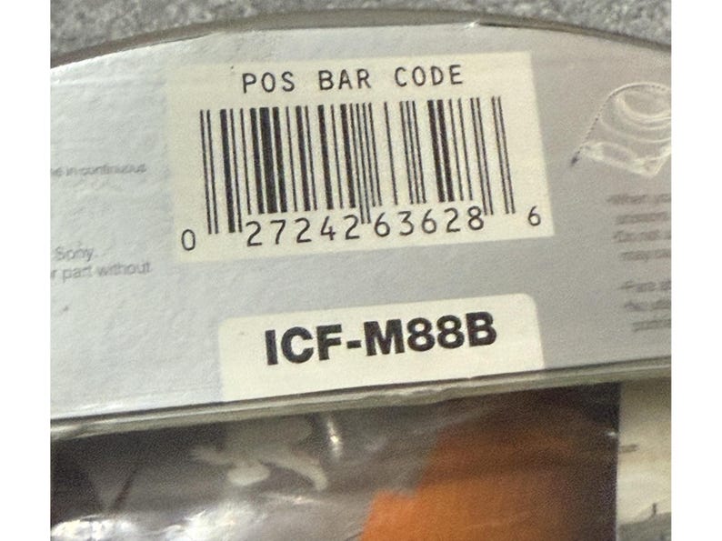 Pu&ograve; includere: Primo piano di un'etichetta di prodotto con un codice a barre e la scritta "POS BAR CODE". Sotto il codice a barre c'&egrave; il numero "0 27242 63628 6". L'etichetta mostra anche la scritta "ICF-M88B".