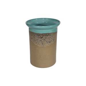 May include: A ceramic utensil holder with a teal glaze on the top and a speckled brown glaze on the bottom.