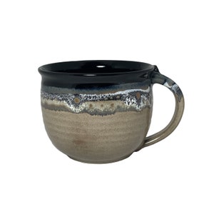 May include: A large, brown ceramic mug with a black rim and a white and blue glaze pattern. The mug has a rounded body and a handle.