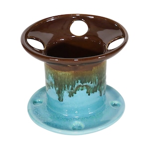 May include: A ceramic toothbrush holder with a brown top and a blue and green base. The top has three holes for toothbrushes.