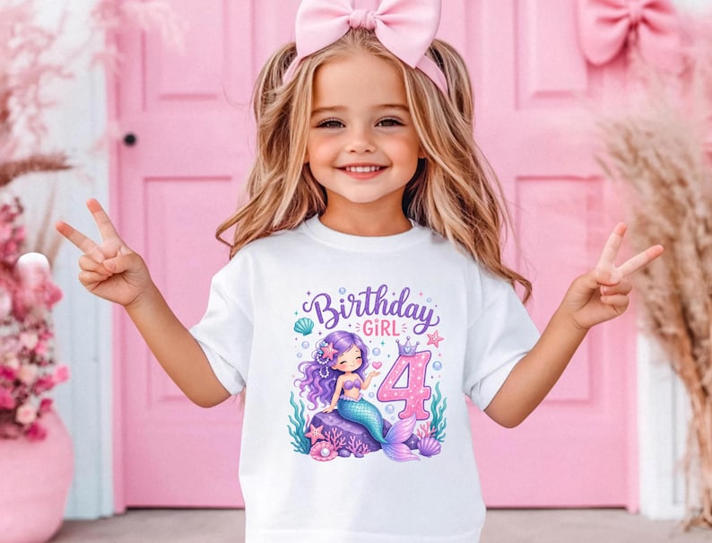 May include: White t-shirt with a colorful mermaid graphic and the text "Birthday Girl 4". The illustration features a purple-haired mermaid, a pink number 4, and aquatic elements. The shirt is designed for a child's birthday celebration.