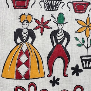 May include: A white fabric with a black and red folk art design. The design features two figures, a woman in a yellow and red dress and a man in red pants and a green hat. There are also flowers and plants in pots.