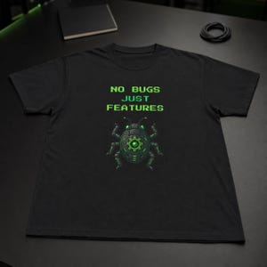 Peut inclure: Un t-shirt noir à manches courtes avec le texte pixelisé vert NO BUGS JUST FEATURES au-dessus d'un graphique représentant un insecte mécanique doté d'un engrenage central et d'accents vert brillant sur le corps et les yeux.