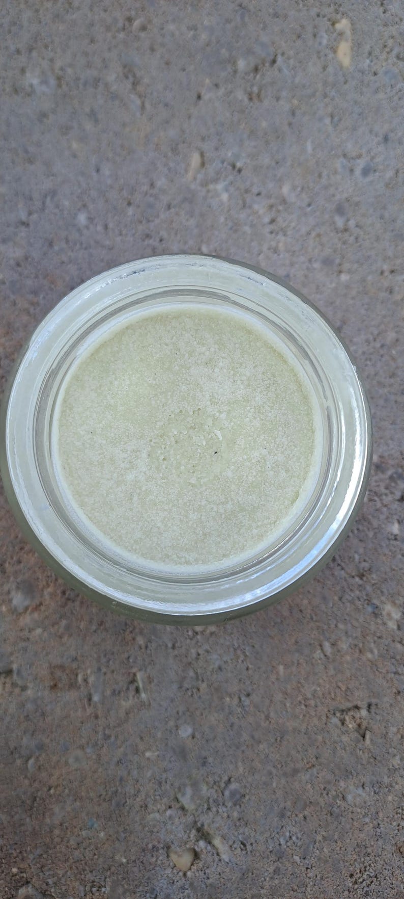 Puede incluir: Un tarro de vidrio transparente lleno de una sustancia cremosa de color verde p&aacute;lido. El tarro tiene una abertura ancha y un dise&ntilde;o sencillo. El contenido parece suave, posiblemente un producto cosm&eacute;tico o para el cuidado de la piel.