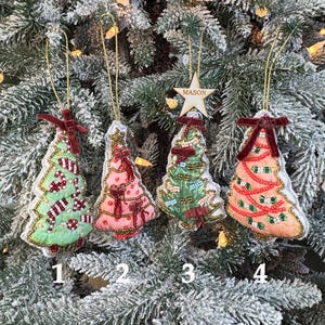 Può includere: Quattro decorazioni per l'albero di Natale con fili dorati. Gli ornamenti sono in tonalità di verde, rosa e arancione, decorati con perline, fiocchi e motivi a bastoncino di zucchero. Un ornamento è una stella di legno con il nome "MASON".