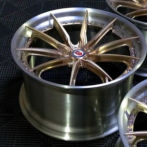 May include: Close-up of three alloy wheels with a multi-spoke design. The wheels have a silver finish with gold-coloured spokes and a central emblem. The wheels are displayed on a black surface.