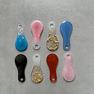 Peut inclure: Huit porte-clés en résine de différentes couleurs et designs. Les porte-clés sont en forme de larme avec un trou en haut pour les attacher à un porte-clés. Les designs comprennent des paillettes, des paillettes dorées et des couleurs unies.