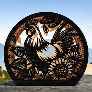 May include: A wooden, laser-cut artwork featuring a rooster and sunflowers within a circular frame. The rooster is black and gold, with intricate details. The frame is dark brown with a woven texture, set against a blurred mountain backdrop.