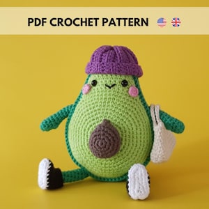 May include: A crocheted avocado plush toy wearing a purple beanie and holding a white crocheted bag. The avocado has a brown pit and pink cheeks.