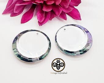 May include: Two circular clear glass pendants with faceted edges that display an iridescent rainbow sheen. Each piece features a small hole at the top for suspension. A logo with a bee icon and the text Vintage Unfinished is visible.