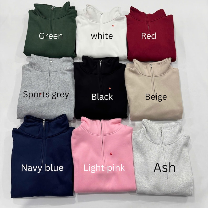 K&ouml;nnte beinhalten: Neun Sweatshirts mit Viertelrei&szlig;verschluss in verschiedenen Farben: Gr&uuml;n, Wei&szlig;, Rot, Sportgrau, Schwarz, Beige, Marineblau, Hellrosa und Asch. Jedes Sweatshirt hat einen Rei&szlig;verschluss und den aufgedruckten Farbnamen.