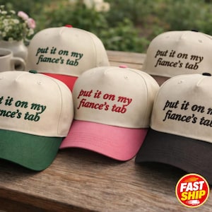 Puede incluir: Cinco gorras de béisbol con coronas de color crema y texto bordado que dice "put it on my fiance's tab". Las gorras presentan viseras de varios colores, incluyendo rojo, verde, rosa y negro, con un diseño estructurado de cinco paneles.