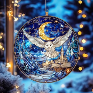 Può includere: Un ornamento rotondo in vetro colorato raffigurante un gufo delle nevi con le ali spiegate, una luna crescente e un castello. L'ornamento ha una cornice color oro e un anello per appenderlo. Lo sfondo è un paesaggio invernale con un cielo stellato.